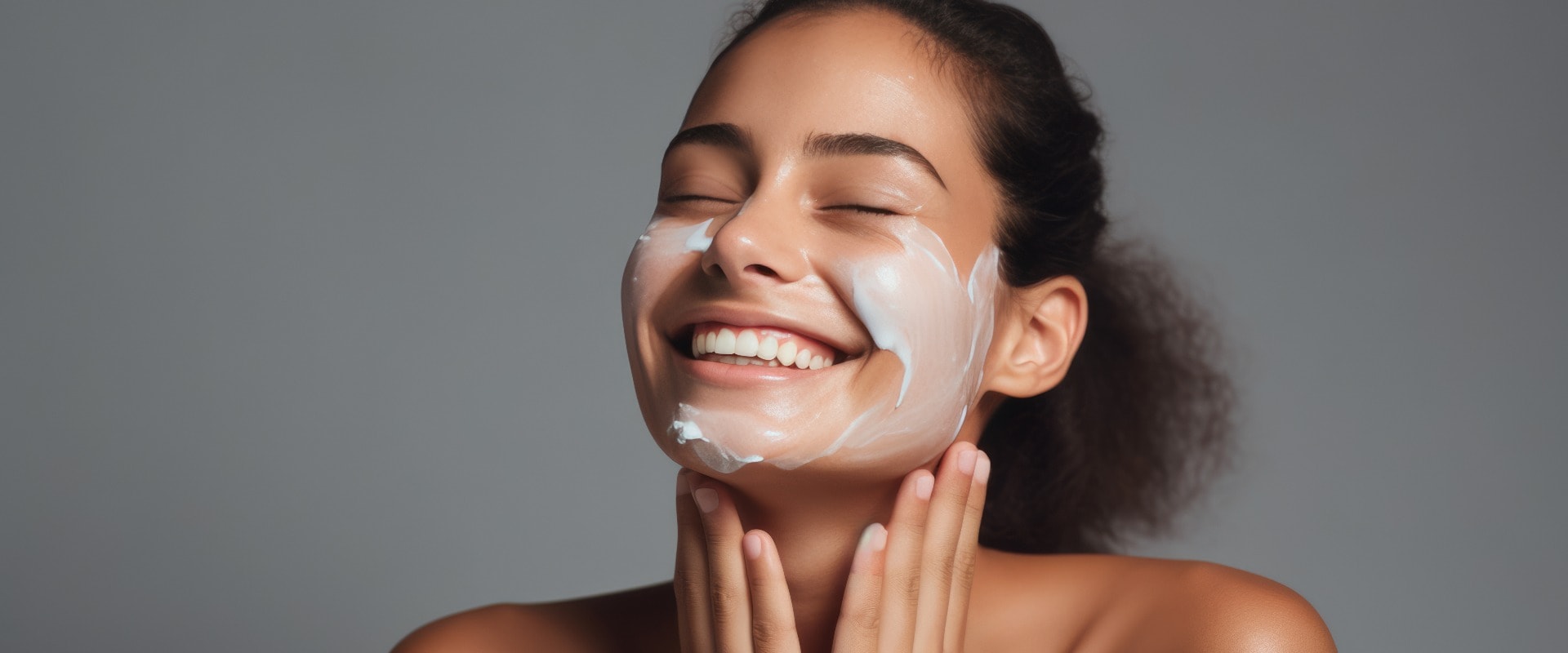 Close up beauty portrait of a laughing beautiful woman applying face cream